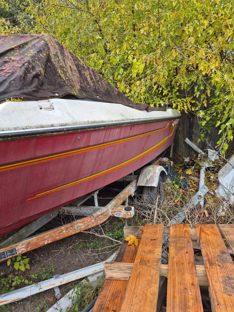 Heavy tractor moving a large boat on a trailer across a wide property