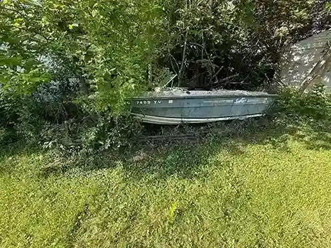 Fiberglass boat staged in a yard for extraction and disposal